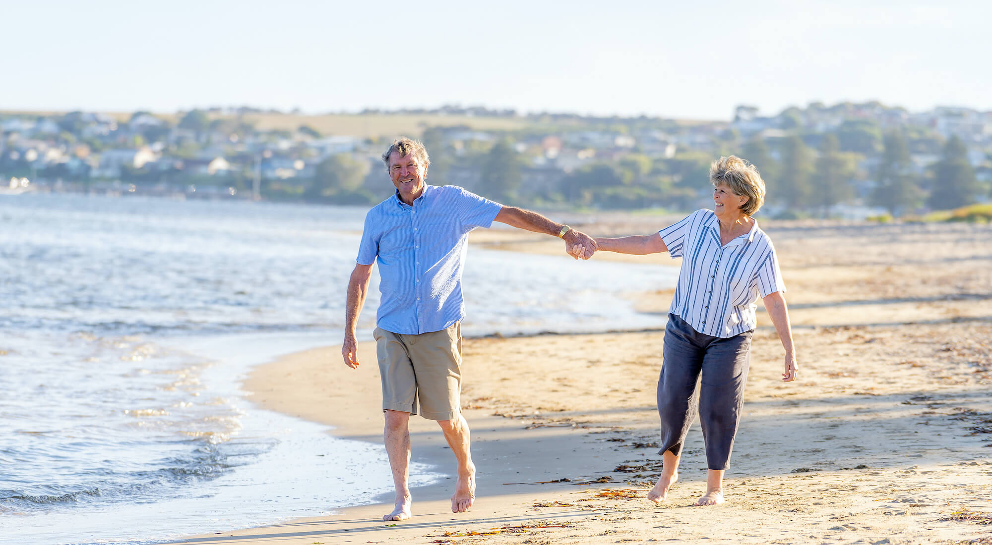 an elderly couple walking along the shoreline